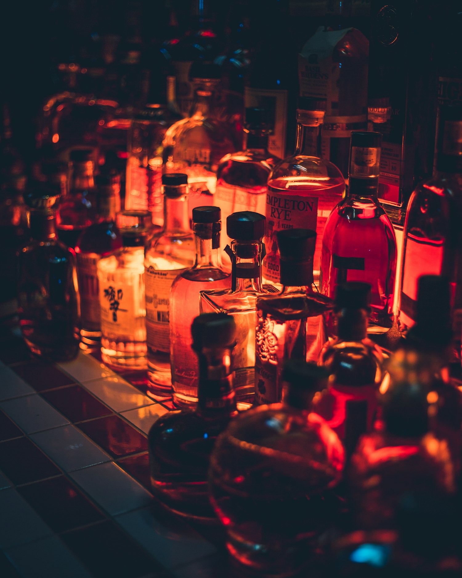 The wall of bottles glowing warm and low inside the shop after dark