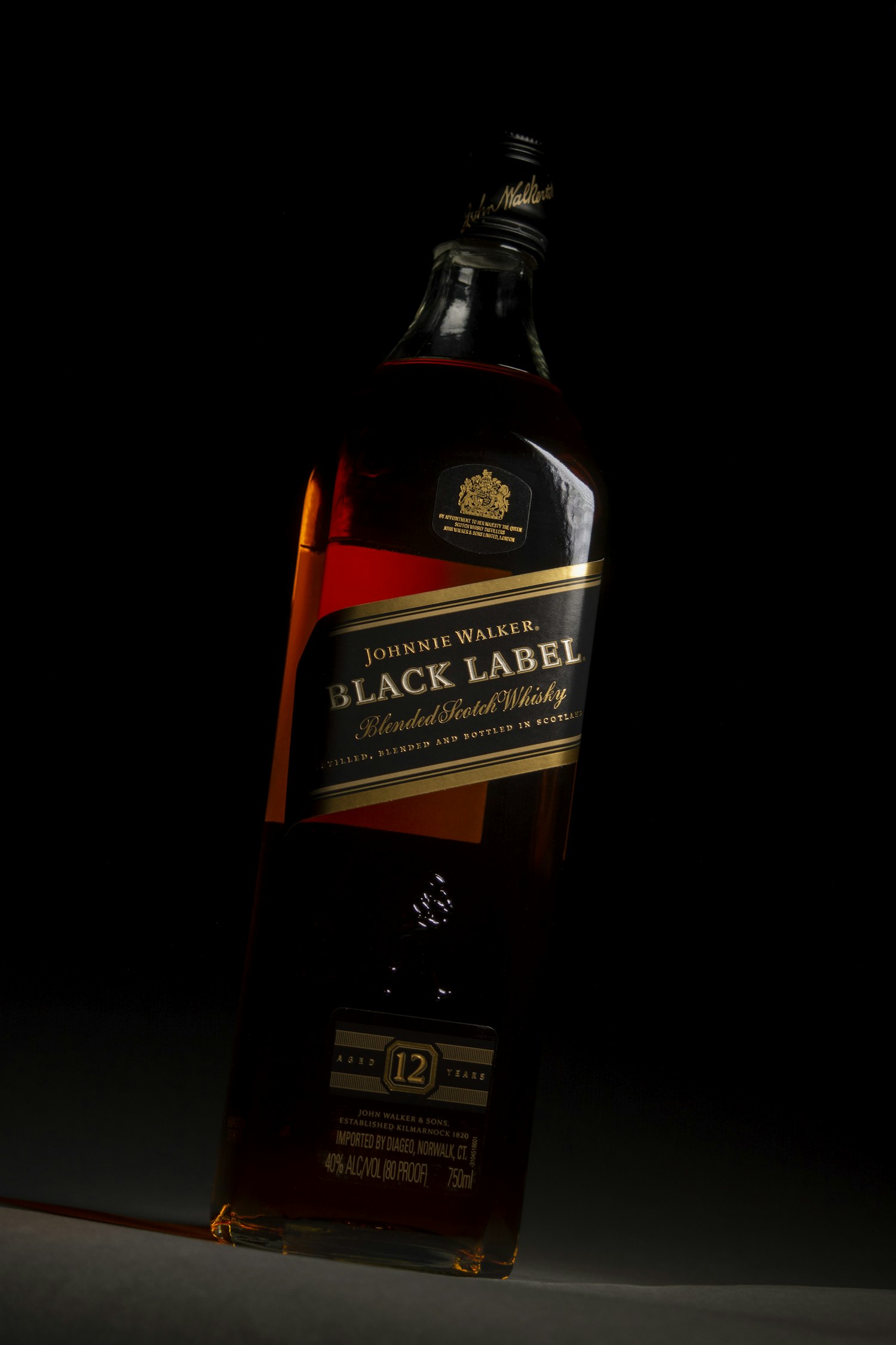 A bottle of whisky lit warm against the dark on the shelf at Brandy's